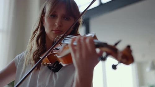 Woman with wavy brown hair plays the violin