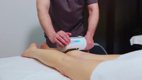Massage Therapist Treating Woman's Leg with Machine