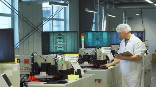 Superviseur blanc effectuant l'inspection finale de la qualité sur les circuits assemblés et comparant le moniteur