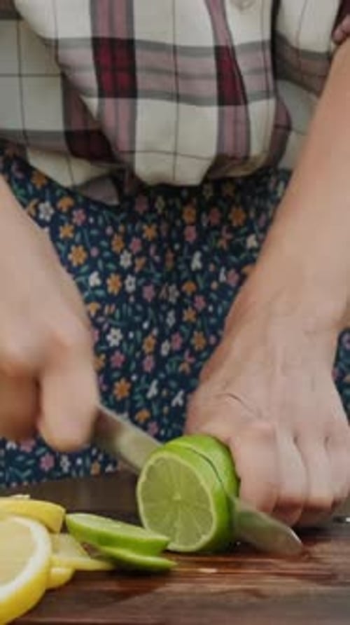 Person Slicing Lime on Cutting Board