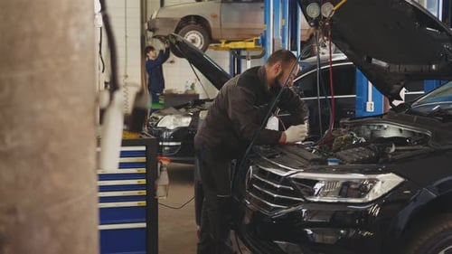 Mechanic man with lamp working at workshop in car service, car repair and maintenance concept