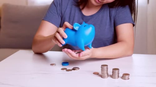 Hands of a woman Picking up coins in the blue piggy bank with blank metaphor separate kind of money