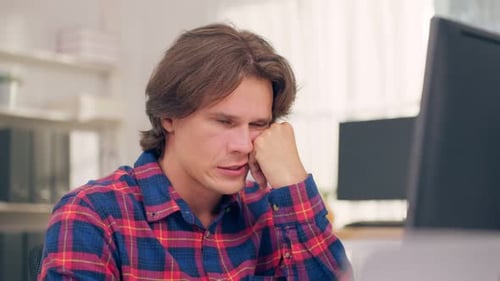 Frustrated Caucasian businessman working on table in office workplace.