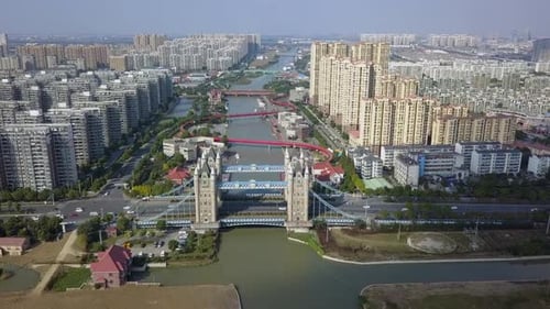 Aerial descends to replica Tower bridge and winding red canal bridge