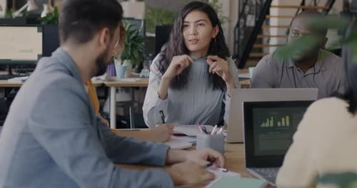 Multiracial Group of Business Partners Talking Looking at Financial Documents in Modern Office