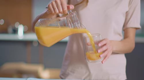Close Up of Woman Pouring Orange Juice Into the Glass From Jar