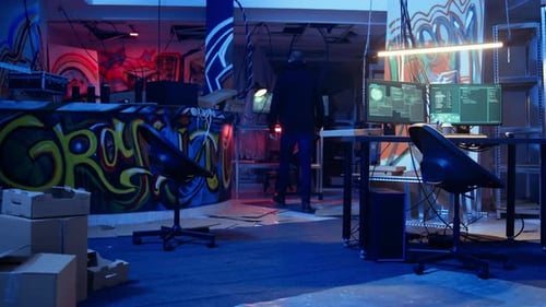 Hooded Hacker Arriving in Hidden Neon Lit Underground Shelter with Graffiti