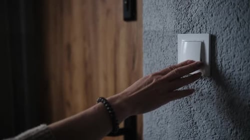 Woman Turning Off Light Switch on Wall