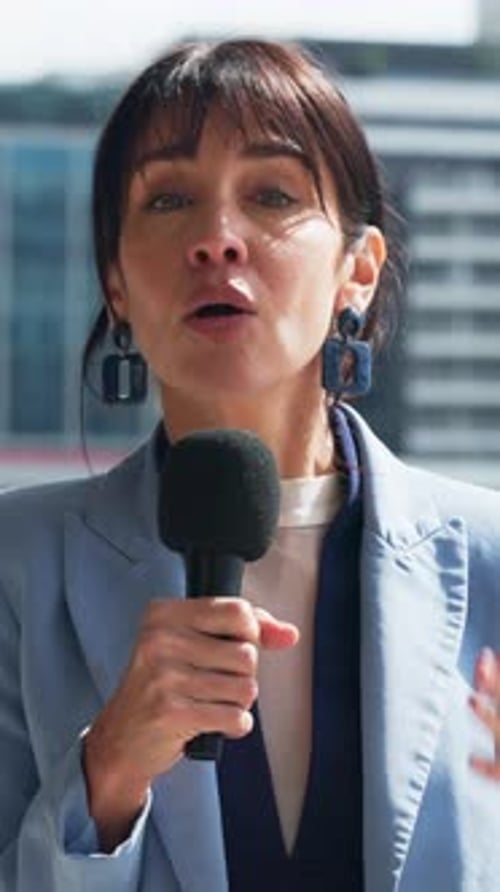 Face, anchor and woman with microphone in city, speaking and live coverage for breaking news story