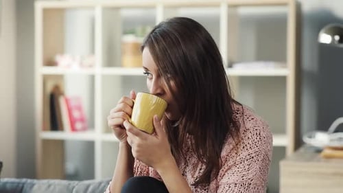 Attractive woman drinking coffee inside living room