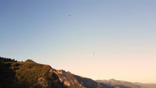 Luftaufnahme von zwei Gleitschirmen, die über dem Berg fliegen