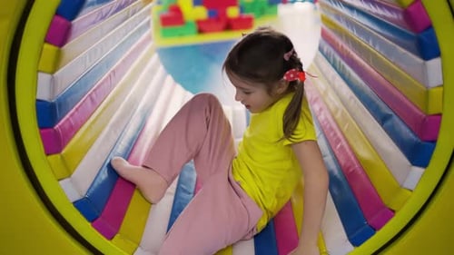 Belle fille jouant au terrain de jeu intérieur dans un tube coloré