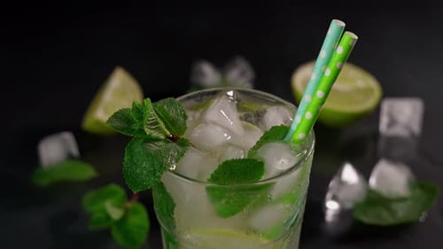 Close-up of Refreshing Mojito Cocktail with lime, ice cubes and green mint leaves on
