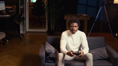 Young Adult Playing Video Game on Couch at Home