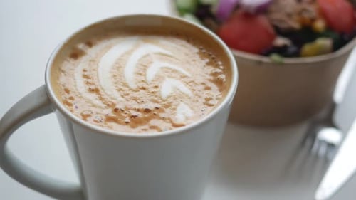Enjoying Coffee and Fresh Fruit Bowl in a Cozy Cafe Setting