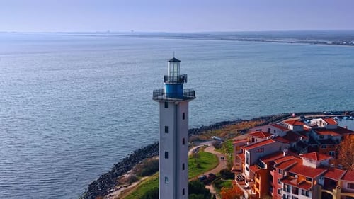 Distancing from a lighthouse against vast peaceful waterscape.
