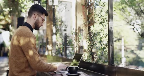 Ein junger Mann benutzt seinen Laptop in einem Café