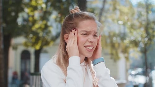 Une femme mécontente se frotte les tempes pour soigner un problème de maux de tête souffrant de migraine et de stress dans la rue