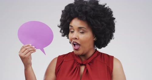 4k video footage of an attractive young woman holding up a speech bubble against a grey background