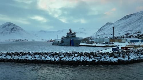 Coastguard ship is docked in a frozen harbor in a snowy landscape in Iceland. Drone dolley shot
