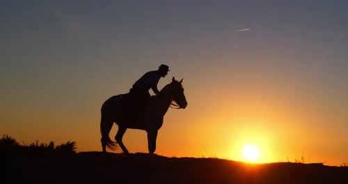 Cowboy Riding Horse Silhouette at Colorful Sunrise
