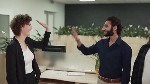 Curly female businessman gives five to his office colleagues