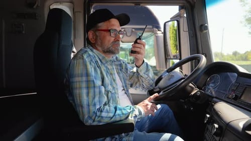 Senior Truck Driver Speaks on the Radio Walkie Talkie with Supervisor Before Leaving