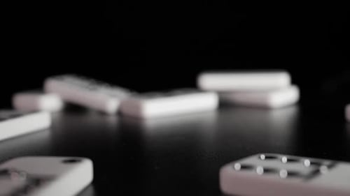 White domino dice fall on a black background. Slow motion
