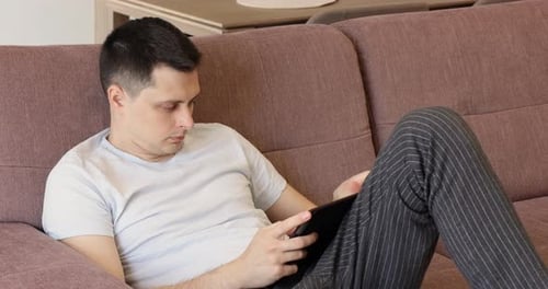Young Adult Relaxing with Tablet on Sofa