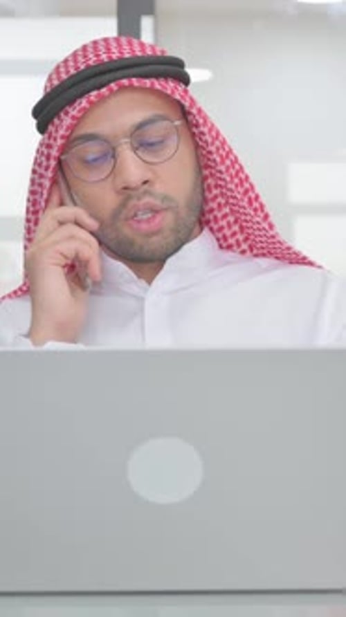 Man Works on Computer, Talking on Cell Phone
