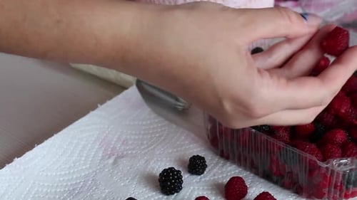 A Woman Puts Raspberries On A Paper Napkin. To Decorate The Meringue Roll With Mascarpone Cream.