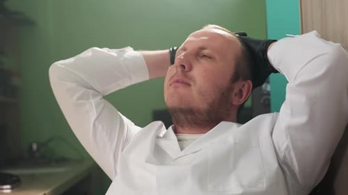 Man Relaxes with Hands Behind Head in Workplace