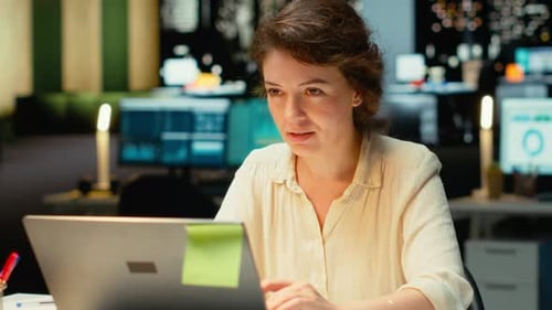 Woman works on laptop in modern office at night