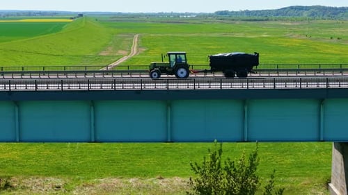 Farming Tractor Driving on Bridge with Trailer Tractor Driving Across Overpass Pulling Loaded Cart