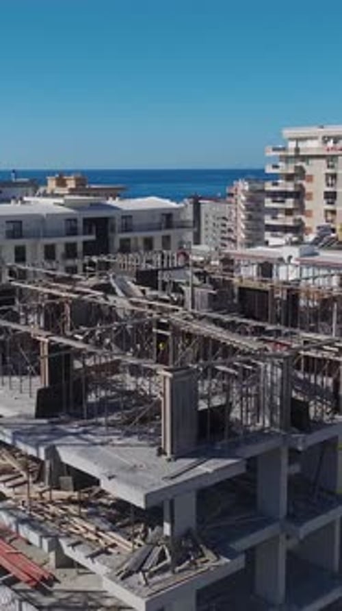 Vídeo vertical de una construcción residencial con trabajadores echando cimientos y construyendo paredes