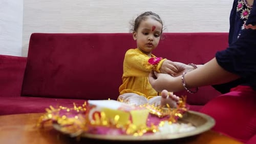 Child Receives Bracelet from Adult Indoors