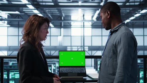Coworkers Reviewing Green Screen Laptop in Data Center
