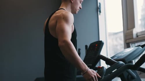 Atleta masculino musculoso se exercitando em esteiras na academia moderna fazendo exercícios físicos