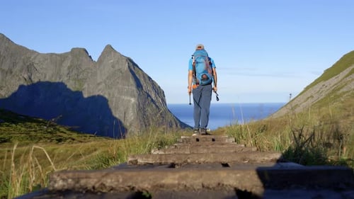 Person With Backback Hiking Down On Rural Way To Kvalvika Beach Lofoten In Morning