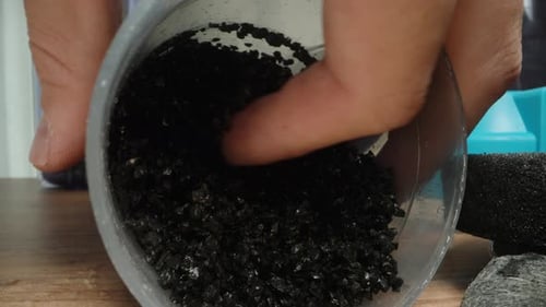 Used carbon water filter, I grind charcoal particles in my hands. Macro.