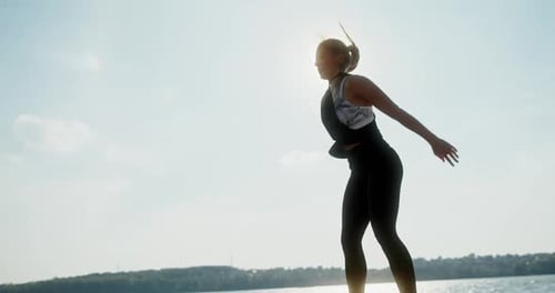 Fit Female Squatting and Jumping on Quay