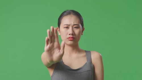 Asian Woman Wearing Sportswear And Disapproving With No Hand Sign On Green Screen Background