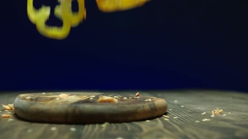 Colorful Bell Pepper Slices Falling on Cutting Board