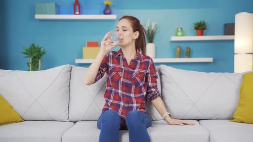 The sick young woman drinks a lot of water.
