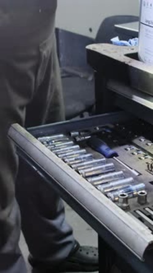 Mechanic Carefully Searches Through Toolbox Selecting Right Part