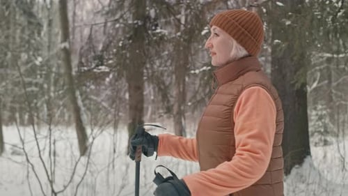 Senior Woman Nordic Walking in Winter Forest