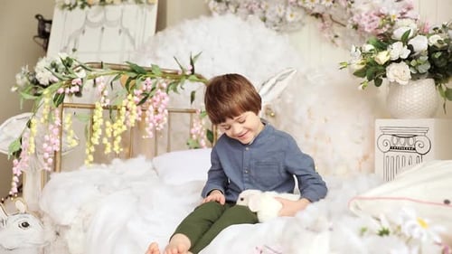 Boy Smiling Holding Rabbit on Decorative Bed