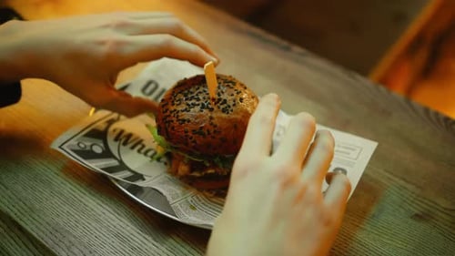 Hands Squeeze a Delicious Hamburger in Restaurant