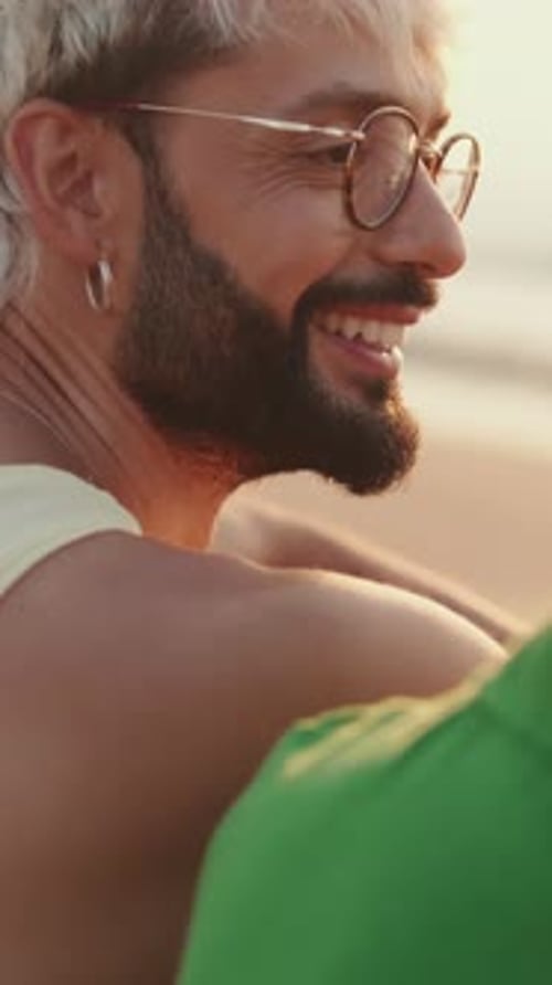 De perto, casal homossexual apaixonado passa tempo juntos sentados na praia ao nascer do sol