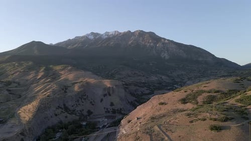 Vol sensationnel au-dessus d'un paysage de campagne aride et brun avec vue sur des montagnes enneigées et déchiquetées